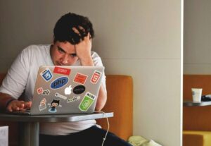 Frustrated person working on laptop.